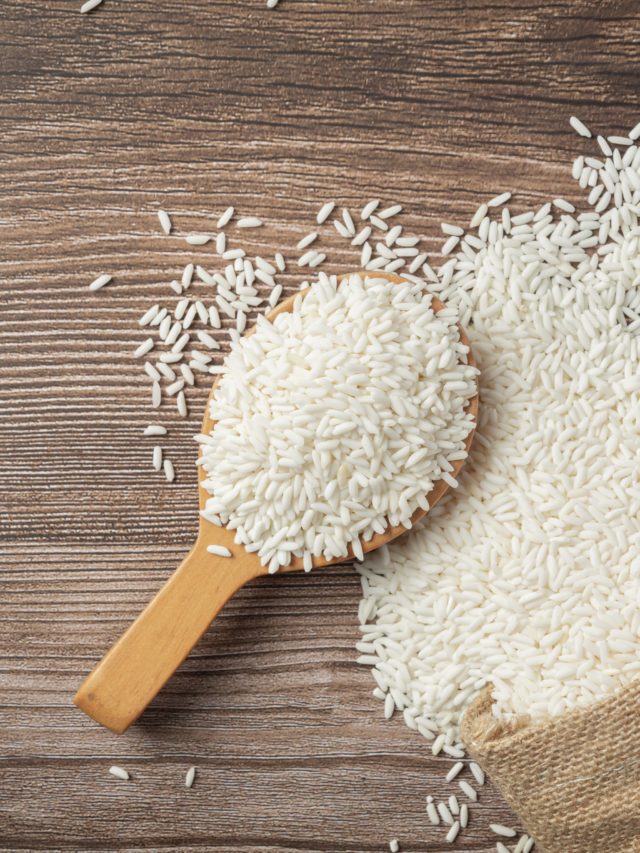 a sack of white rice and wooden spoon place on wooden floor