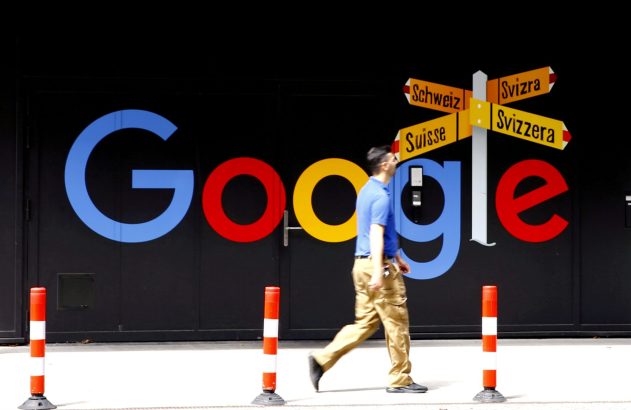 Homem caminha por fachada com logo colorido do Google. Sinal aponta Suíça em 4 idiomas. Postes de segurança.
