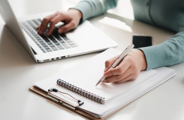 A imagem mostra uma pessoa sentada em uma mesa, fazendo cálculos em um bloco de notas. Ela também usa um notebook. (Foto: Shutterstock / PaeGAG)