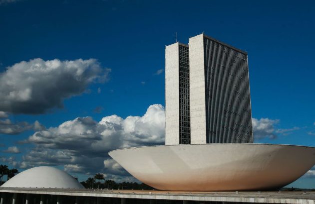O Congresso Nacional do Brasil em Brasília, com suas duas torres e cúpulas, sob céu azul com nuvens.