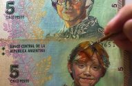 Notas de 5 pesos argentinas pintadas com Harry Potter e Ron Weasley. Uma mão pincela o cabelo.
