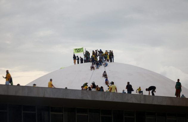 Pessoas em uma grande cúpula branca, algumas descem com cordas. Uma faixa está no topo.