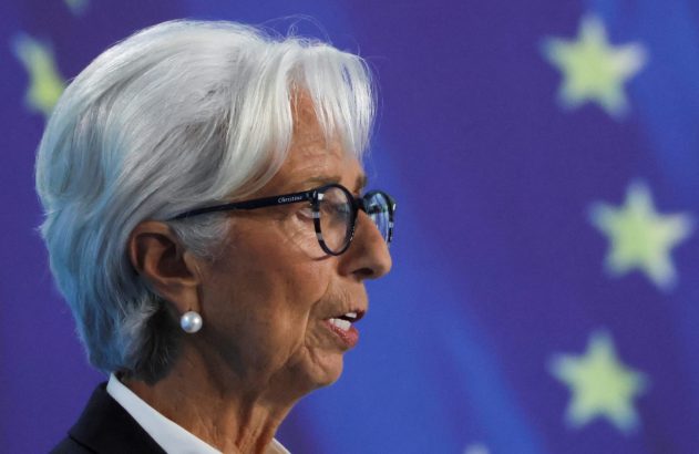 Christine Lagarde, de perfil, com cabelo branco e óculos, discursando. Fundo azul com estrelas da UE.
