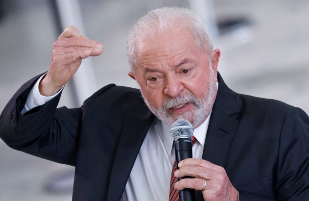 Homem de barba branca discursa ao microfone, gesticulando. Veste terno e camisa.
