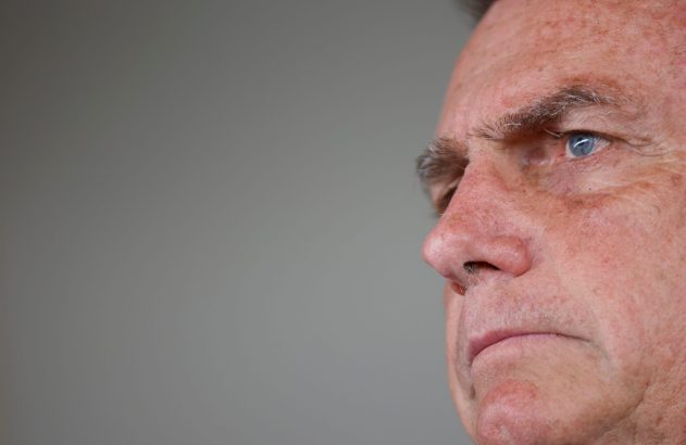 Rosto de homem em close-up, de perfil, com olho azul e fundo cinza.