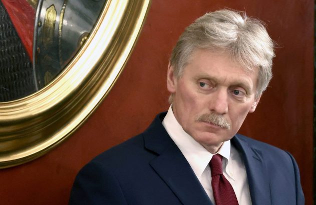 Homem de bigode e cabelo grisalho em terno azul e gravata vermelha olha para o lado. Moldura dourada ao fundo.