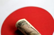 Nota de 10.000 ienes enrolada, repousando sobre o círculo vermelho da bandeira do Japão.