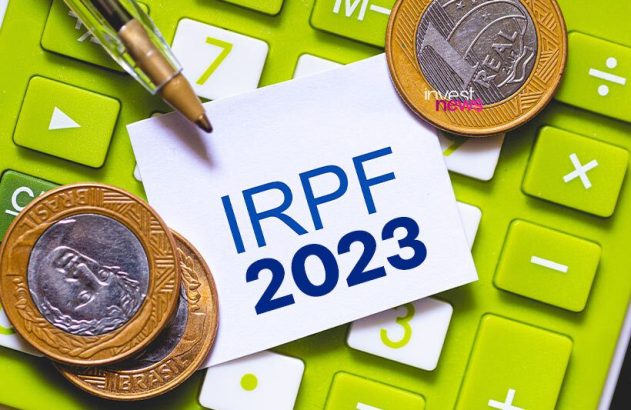 Nota com "IRPF 2023", caneta, moedas de Real e calculadora verde.
