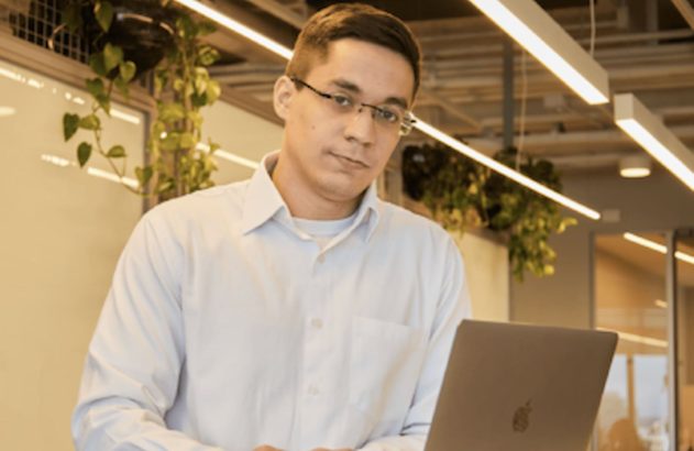 Homem mexendo em um computador no meio de um escritório