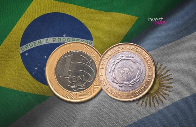 Moeda de 1 Real brasileiro e moeda argentina sobrepostas, sobre as bandeiras do Brasil e da Argentina.