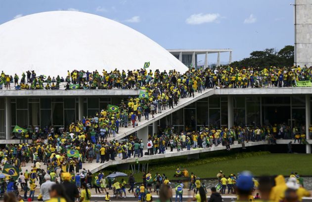 Multidão com bandeiras do Brasil protesta no Congresso Nacional; um cartaz diz 'Intervenção Militar'.