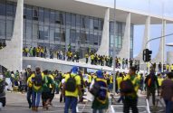 Manifestantes vestidos de verde e amarelo com bandeiras do Brasil em edifício governamental.