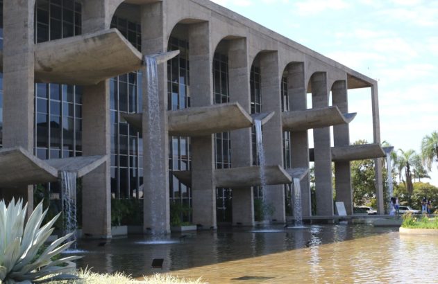 Edifício de concreto com arcos e múltiplas cascatas de água caindo em um espelho d'água.