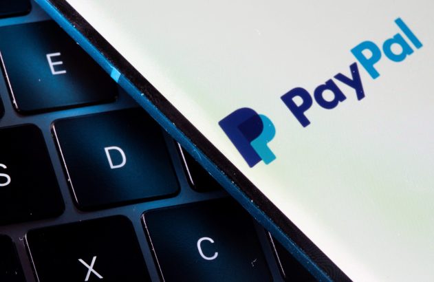 Logotipo do PayPal em tela de aparelho digital, diagonalmente sobre teclado de computador.