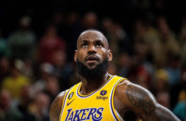 LeBron James em quadra, com uniforme dos Lakers, olhando para cima.