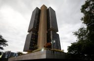 Banco Central do Brasil em Brasília: edifício alto com quatro blocos de vidro escuro e núcleo central, sob céu nublado.