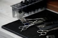 Ferramentas de barbeiro: tesouras e pentes sobre um tapete preto.