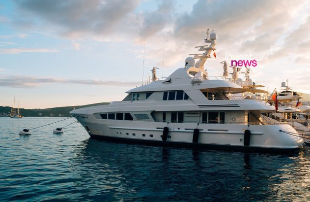 Iate branco grande atracado em marina ao pôr do sol, com outros barcos e céu nublado.