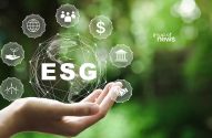 Mão segura globo digital com "ESG" e ícones de ambiente, social e governança. Fundo verde desfocado.