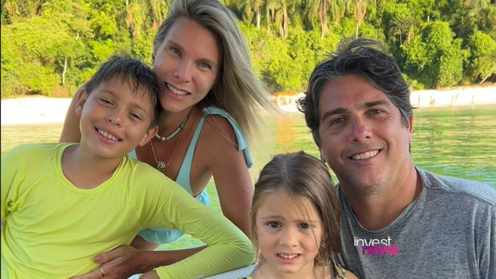 Família de 4 (casal, menino, menina) sorrindo para câmera em cenário natural com água e vegetação.