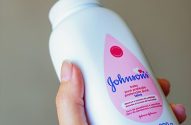 Mão segurando um frasco de talco Johnson's Baby com rótulo rosa.