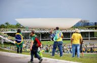 Multidão com roupas verde-amarelas em frente ao Congresso Nacional em Brasília, sob céu parcialmente nublado.