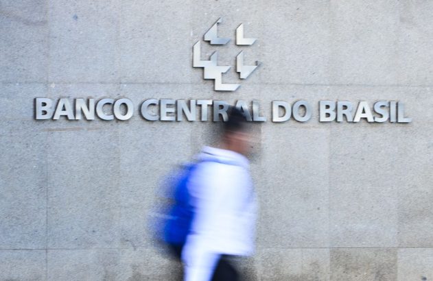 Placa do Banco Central do Brasil com logo e pessoa em movimento borrado.