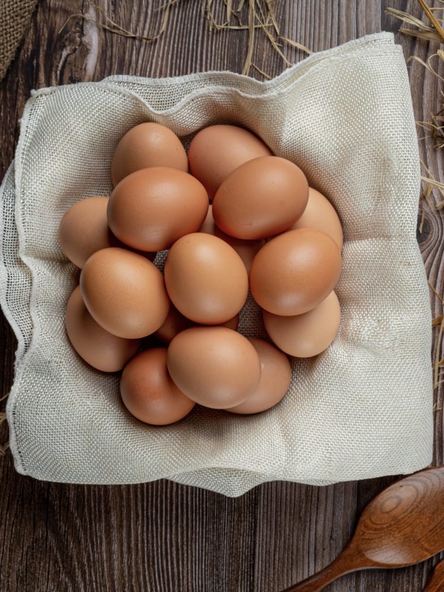 Eggs in cups on burlap with dry grass.