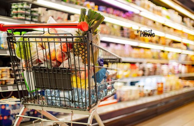 Carrinho de compras cheio de frutas e mantimentos em supermercado.