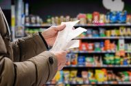 Mãos de pessoa checando vários recibos de compra em supermercado.