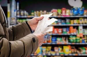Mãos de pessoa checando vários recibos de compra em supermercado.