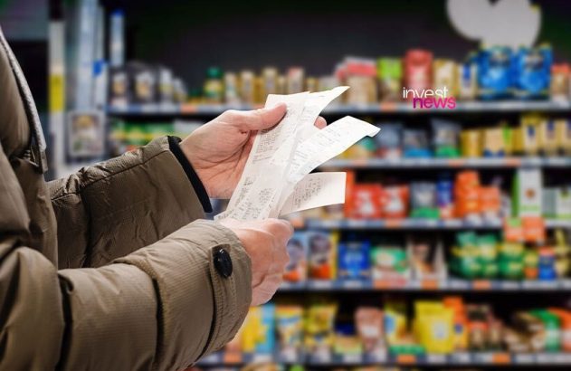 Mãos de pessoa checando vários recibos de compra em supermercado.