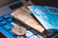Cédulas e moeda de Real brasileiro sobre uma calculadora. Finanças e investimentos.