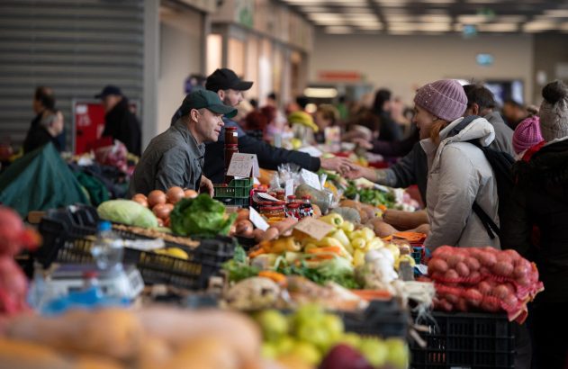 Mercado movimentado: Homem e mulher conversam em bancas de frutas, legumes e produtos frescos.