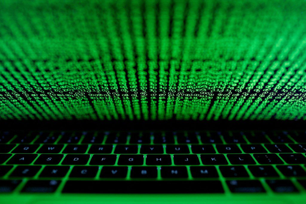 Teclado de laptop iluminado em verde com código binário escorrendo na tela.