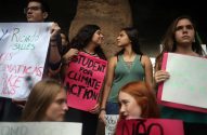 Jovens protestam com cartazes, um rosa diz "STUDENT FOR CLIMATE ACTION".