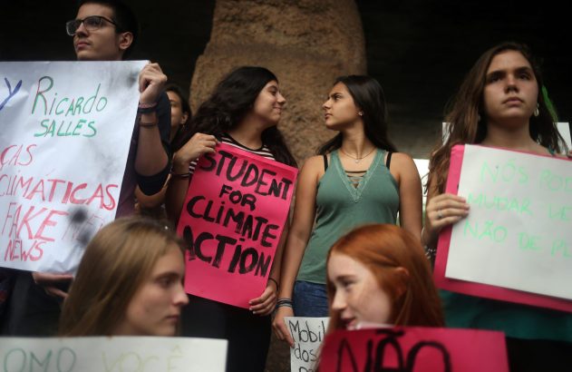 Jovens protestam com cartazes, um rosa diz "STUDENT FOR CLIMATE ACTION".