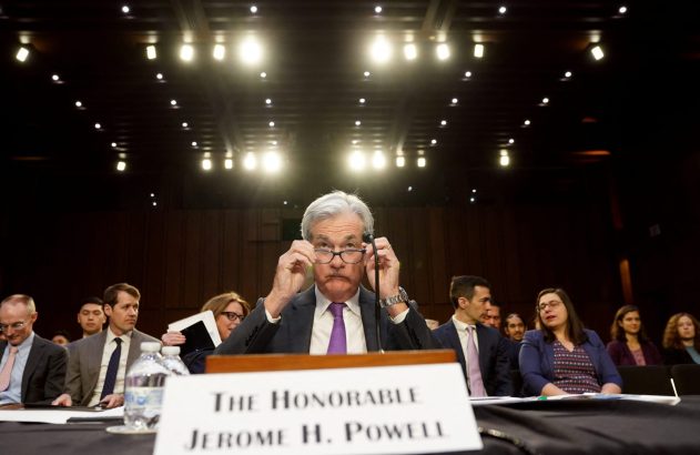 Jerome Powell, em audiência, ajusta os óculos e olha fixamente para a frente.