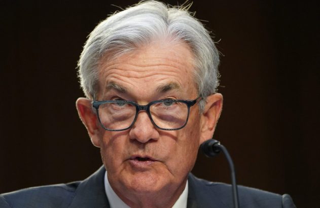 Close-up: homem de óculos e cabelo grisalho falando em microfone.