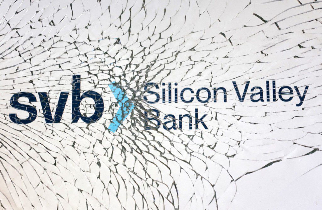 Logo do Silicon Valley Bank (SVB) em superfície quebrada, com trincas irradiando do ícone central azul.