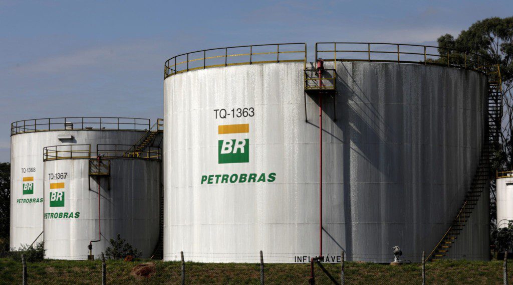 Grandes tanques brancos de petróleo da Petrobras, marcados com logos BR, identificações e aviso 'Inflamável'.