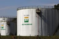 Grandes tanques brancos de petróleo da Petrobras, marcados com logos BR, identificações e aviso 'Inflamável'.