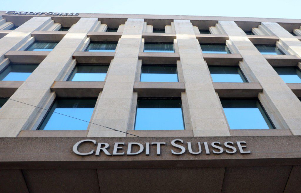 Fachada do edifício Credit Suisse com janelas refletindo o céu azul.