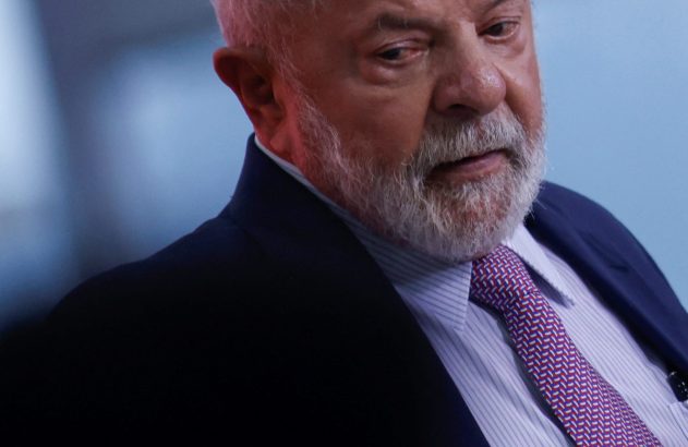 Luiz Inácio Lula da Silva, com cabelo e barba brancos, terno e gravata roxa, olhando pensativo.