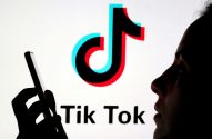 Silhueta de pessoa usando smartphone, com o logotipo do TikTok em um fundo claro.