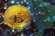 Moeda de Bitcoin dourada em destaque sobre teclado digital, com dados financeiros de mercado ao fundo.