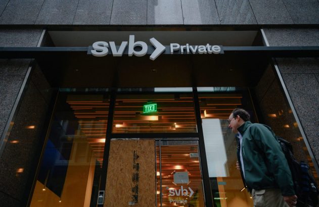 Homem anda em frente à fachada do SVB Private com porta/janela parcialmente vedada por madeira.