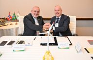 CEO da Petrobras e Equinor apertam as mãos em acordo, com turbina eólica e bandeiras do Brasil e Noruega.