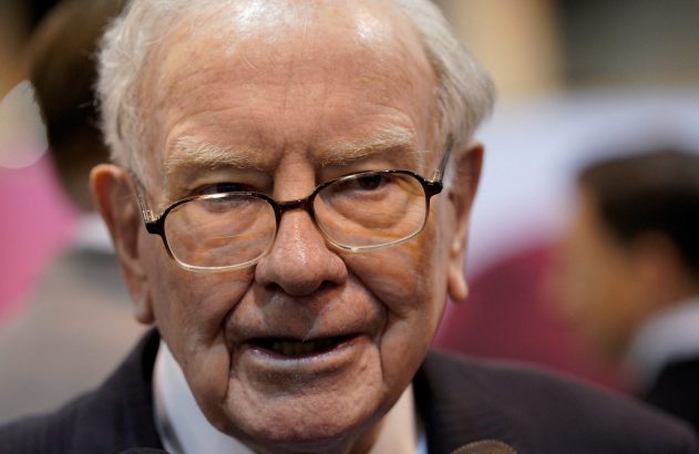 Rosto de Warren Buffett, idoso com óculos, olhando e sorrindo.