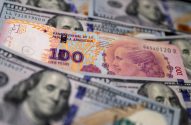 Cédula de 100 pesos argentinos sobre notas de 100 dólares americanos.